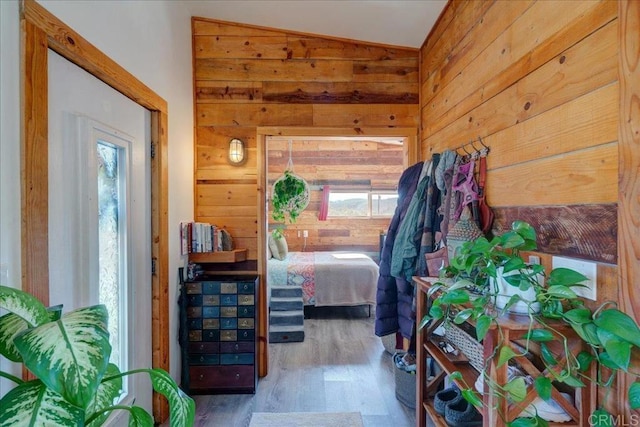 bedroom featuring wood walls, wood finished floors, and lofted ceiling