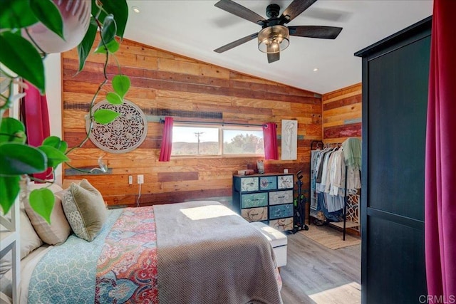 bedroom with wood walls, wood finished floors, ceiling fan, and vaulted ceiling