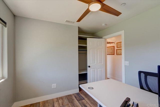 unfurnished office featuring dark wood finished floors, visible vents, a ceiling fan, and baseboards