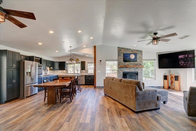 living area with light wood finished floors, ceiling fan, vaulted ceiling, and visible vents
