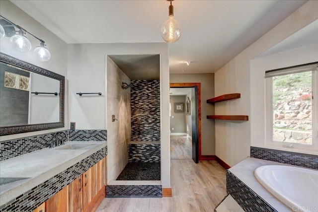 full bathroom with a tile shower, a bath, wood finished floors, and vanity