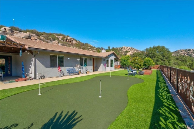 rear view of property featuring a mountain view, a fenced backyard, stucco siding, and a patio area