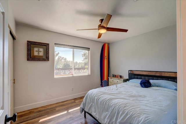 bedroom featuring a ceiling fan, wood finished floors, and baseboards