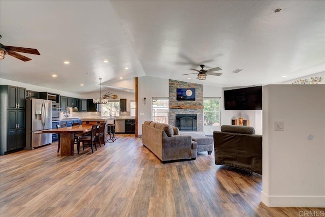 living area featuring visible vents, ceiling fan, light wood-style floors, and lofted ceiling