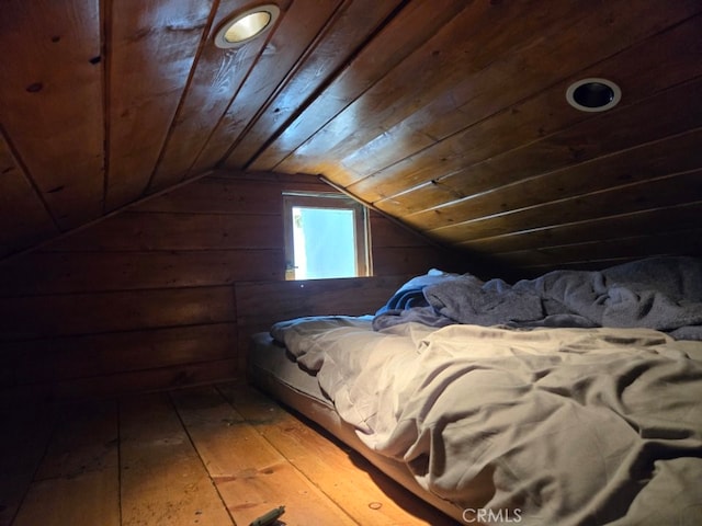 bedroom with wooden ceiling, vaulted ceiling, wood finished floors, and wood walls