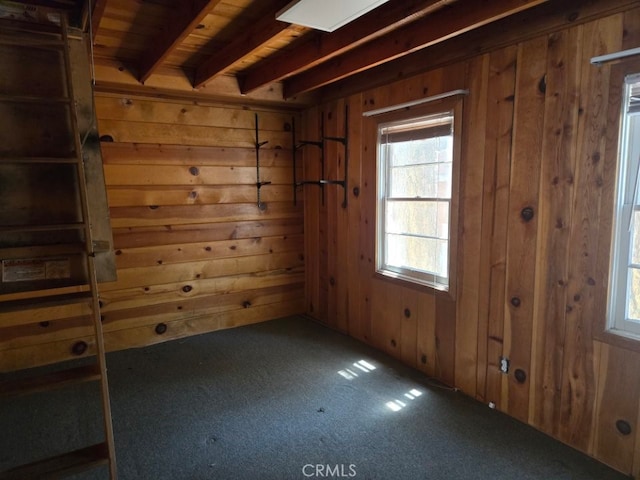 spare room featuring wood ceiling, dark carpet, beam ceiling, and wooden walls