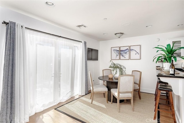 dining room featuring baseboards, visible vents, wood finished floors, and recessed lighting