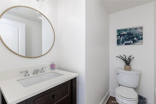 half bathroom featuring vanity, toilet, and baseboards