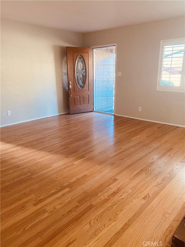 spare room featuring baseboards and light wood finished floors