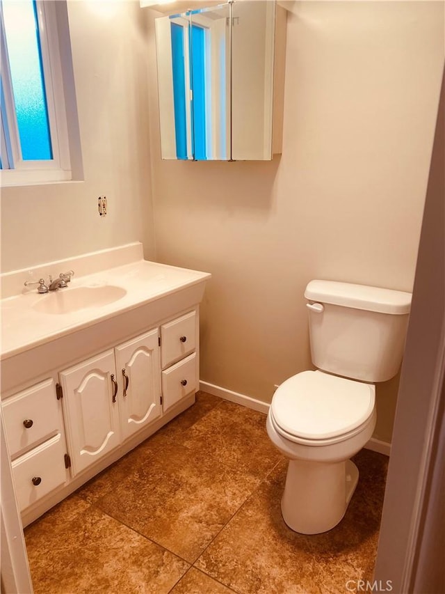 bathroom featuring toilet, vanity, and baseboards