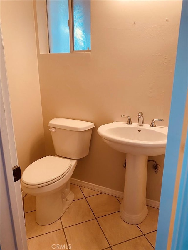 bathroom featuring tile patterned flooring, baseboards, a sink, and toilet