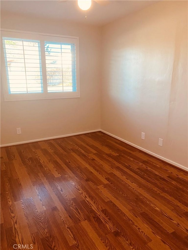 empty room featuring dark wood-type flooring and baseboards