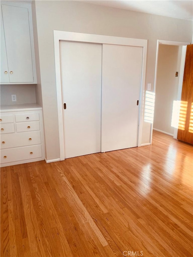 unfurnished bedroom with light wood finished floors and a closet