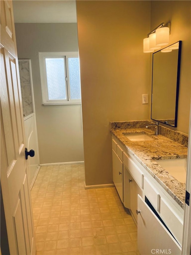 bathroom with double vanity, baseboards, a sink, and tile patterned floors