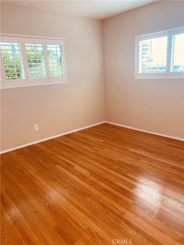 spare room featuring light wood finished floors and baseboards