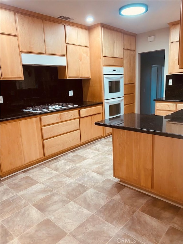 kitchen with white appliances, visible vents, decorative backsplash, and light brown cabinetry