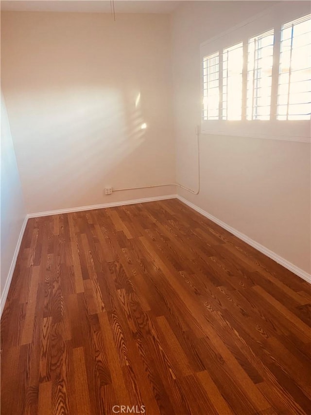 unfurnished room featuring baseboards and wood finished floors