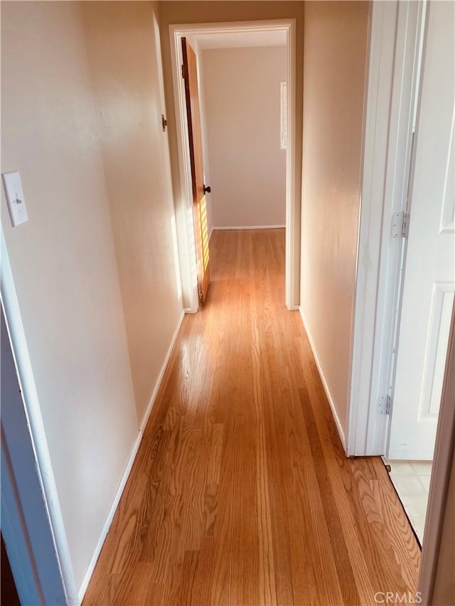 corridor with baseboards and light wood-style floors