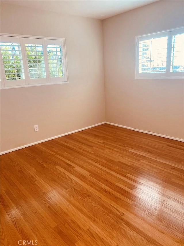 spare room with baseboards and light wood-style floors