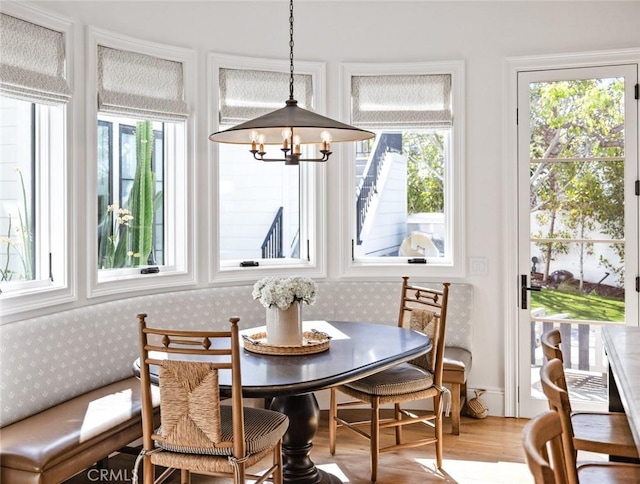 dining room featuring light wood-type flooring, wallpapered walls, a chandelier, and breakfast area