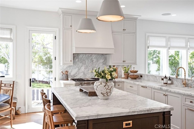 kitchen featuring a healthy amount of sunlight, decorative light fixtures, a sink, and decorative backsplash