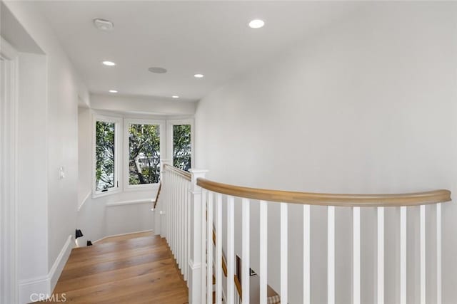 hall with light wood finished floors, an upstairs landing, and recessed lighting