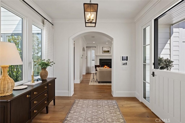 entryway with light wood-type flooring, plenty of natural light, and crown molding