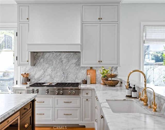 kitchen featuring white cabinets, light stone countertops, stainless steel appliances, and a sink