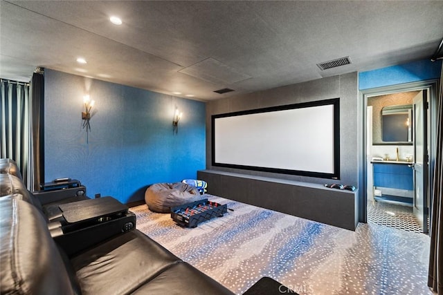 home theater room featuring recessed lighting, carpet flooring, a textured wall, and visible vents