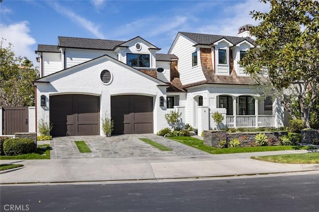 view of front of home with a garage, decorative driveway, and covered porch