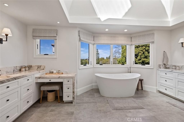 full bath with a healthy amount of sunlight, a soaking tub, baseboards, and recessed lighting