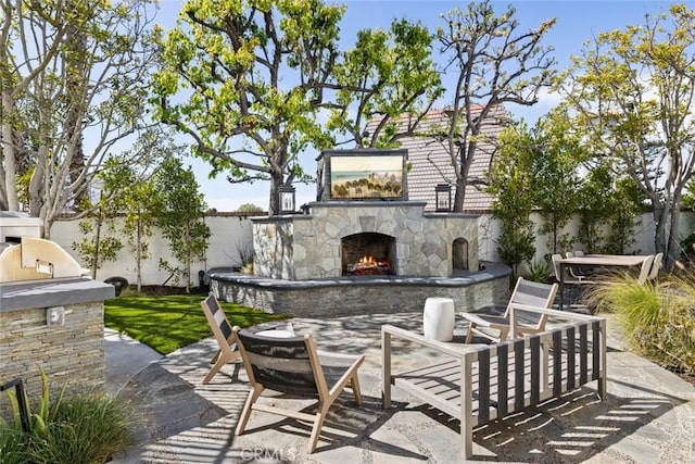 view of patio / terrace featuring an outdoor stone fireplace and fence