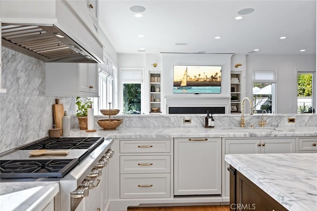 kitchen featuring light stone counters, a sink, white cabinetry, and custom range hood