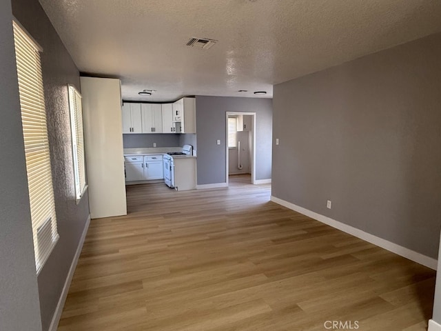 interior space with visible vents, white cabinetry, light wood-style floors, light countertops, and white gas range oven