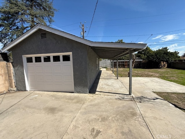 garage with concrete driveway and fence