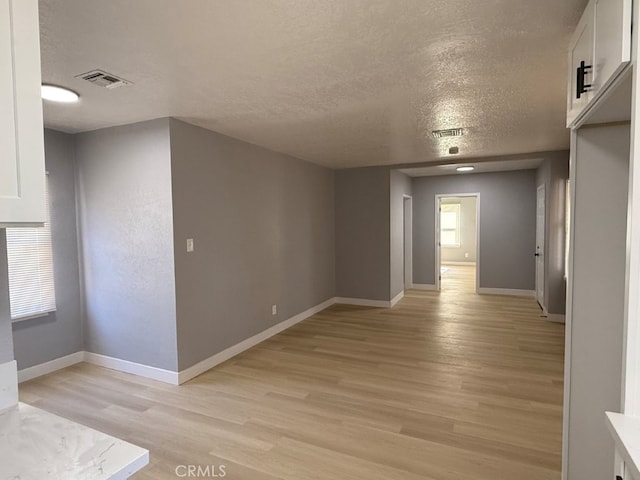 spare room with light wood-style floors, visible vents, and baseboards