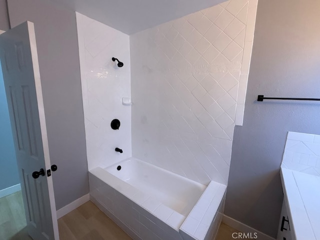 full bath with tiled shower / bath combo, baseboards, and wood finished floors