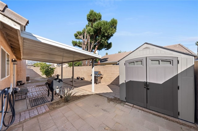 view of patio / terrace featuring a fenced backyard, a grill, a storage unit, and an outdoor structure