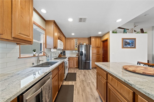 kitchen with glass insert cabinets, visible vents, appliances with stainless steel finishes, and light stone counters