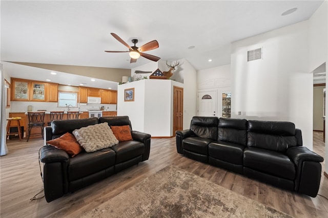 living area with visible vents, light wood-style flooring, ceiling fan, high vaulted ceiling, and recessed lighting