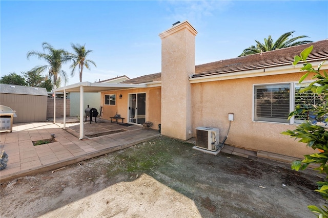 back of house with an outbuilding, a storage shed, stucco siding, ac unit, and a patio area