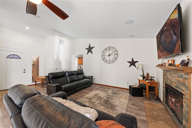 living room with recessed lighting, visible vents, vaulted ceiling, a stone fireplace, and baseboards