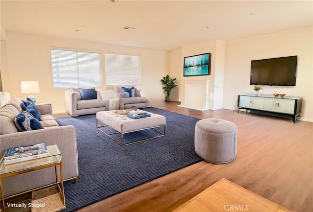 living room with visible vents, baseboards, and wood finished floors