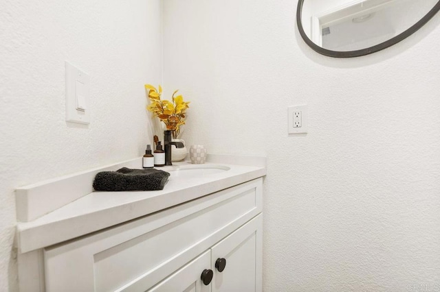 bathroom with a textured wall and vanity