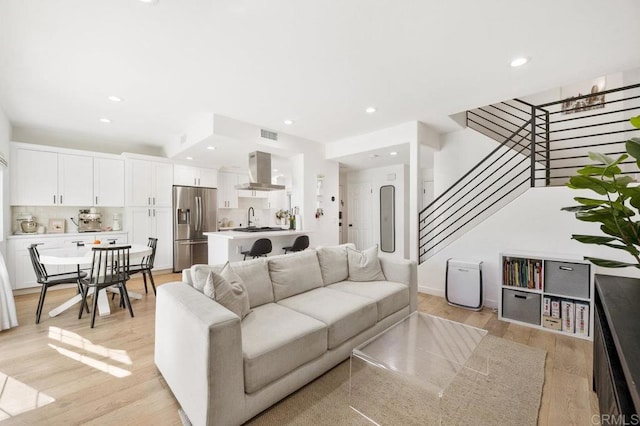 living area with light wood-type flooring, stairway, and recessed lighting