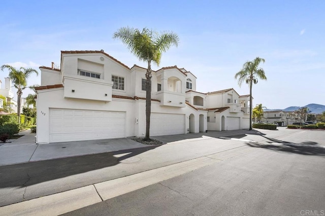 mediterranean / spanish-style house with a garage, driveway, a residential view, and stucco siding