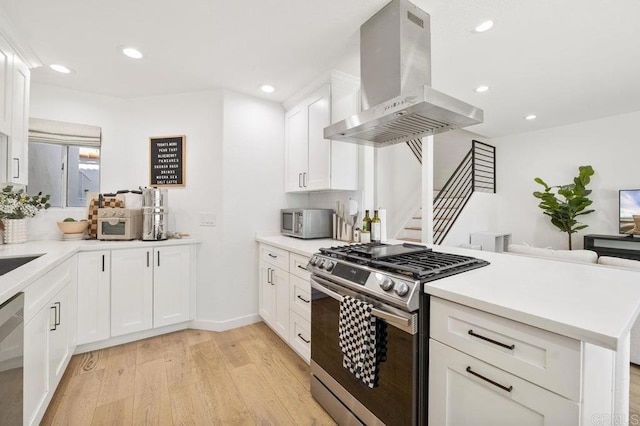 kitchen with stainless steel appliances, light countertops, a peninsula, and island range hood