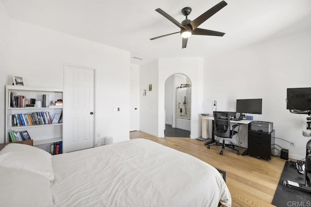 bedroom with ceiling fan, arched walkways, and wood finished floors