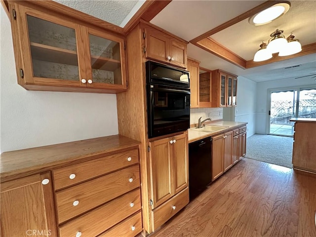 kitchen featuring brown cabinets, a raised ceiling, light countertops, glass insert cabinets, and black appliances