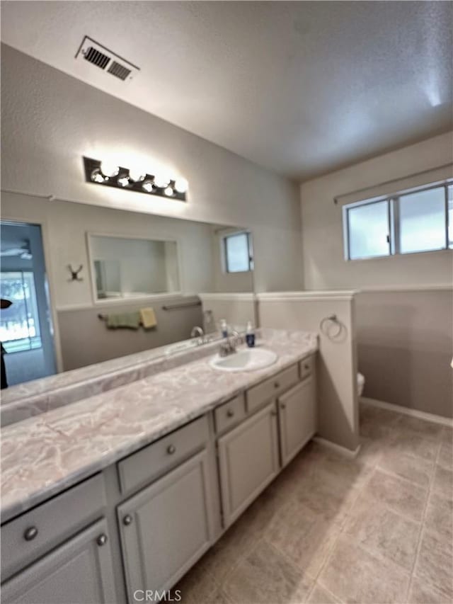 bathroom with toilet, baseboards, visible vents, and vanity